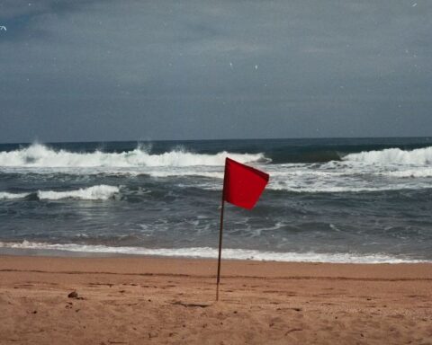 Red Flag on beach in foreground with ominous looking waves and sky in background