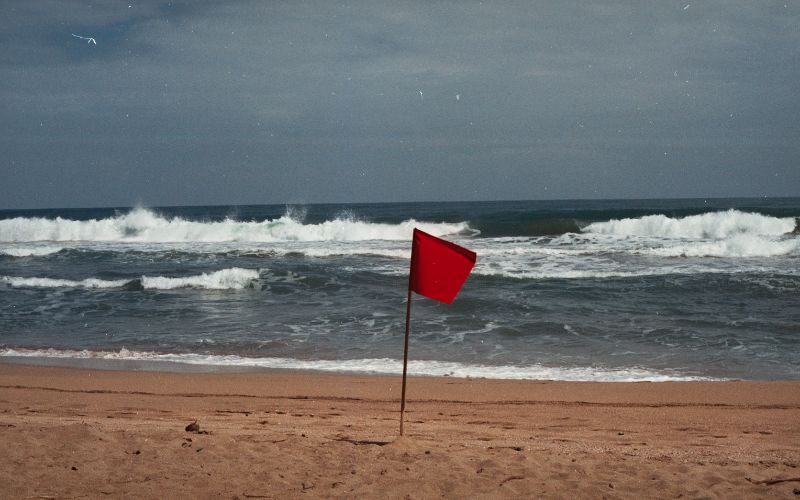 Red Flag on beach in foreground with ominous looking waves and sky in background