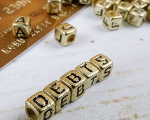 gold colored letter blocks spelling debts